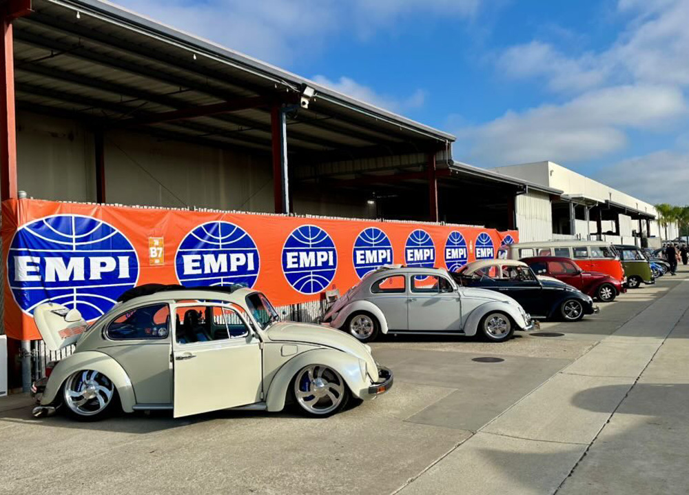Lineup of classic Volkswagen Beetles and a VW Bus in front of an EMPI banner at the EMPI 70th Anniversary Open House